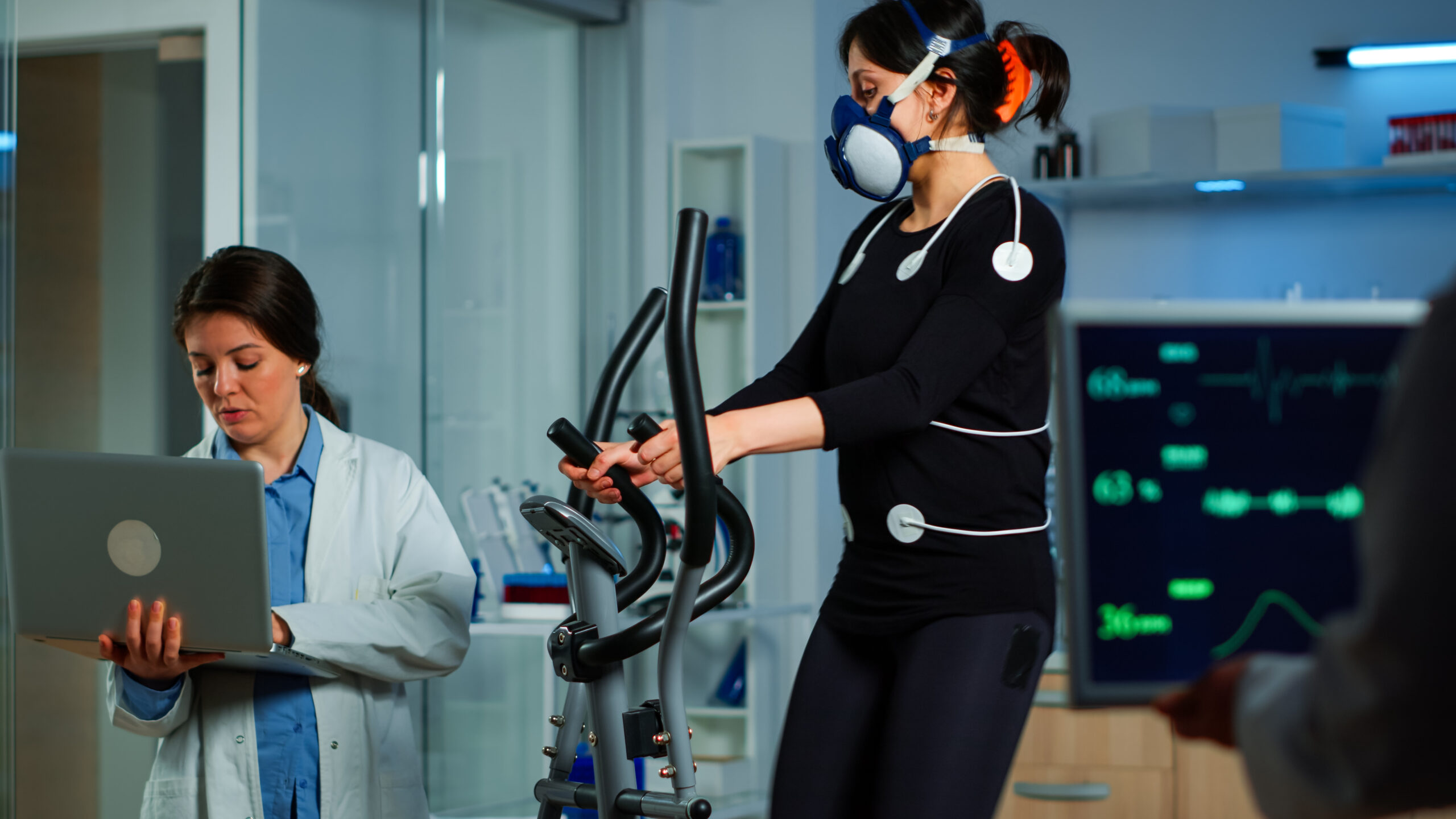 Medical researcher using laptop while measuring sportsman endurance
